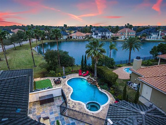 Incredible view of the pool and spa with waterfall feature, green space, and both covered and uncovered lounging areas.