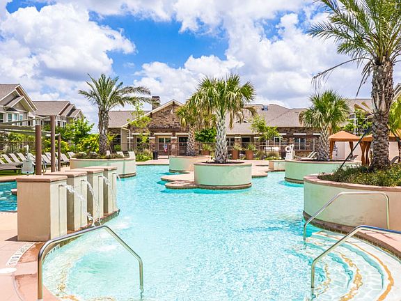 Resort inspired pool with lush palm trees and fountains