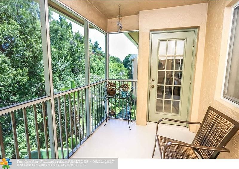 Spacious, enclosed private balcony with view of lush landscaping.