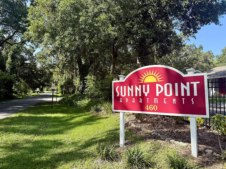 Welcome to Sunny Point Apartments nestled in lush greenery, offering a serene and inviting atmosphere.