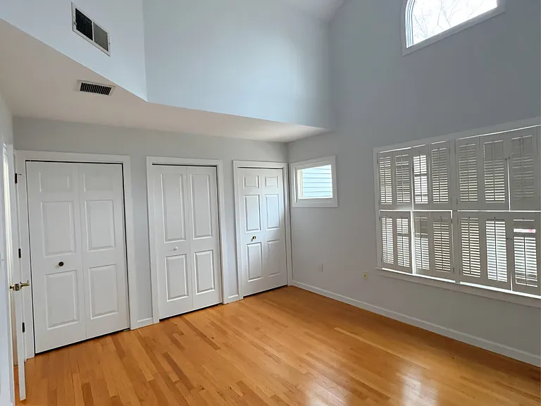Spacious bedroom with vaulted ceilings, hardwood floors, and abundant natural light.