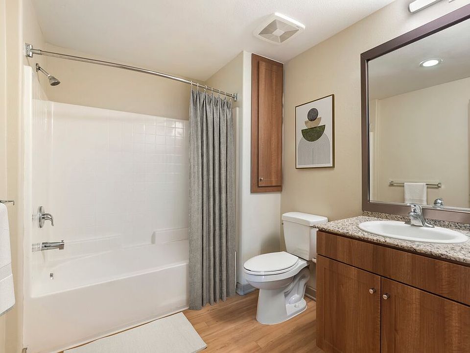 Renovated Package I bath with oak cabinetry, beige speckled granite countertops, and hard surface flooring
