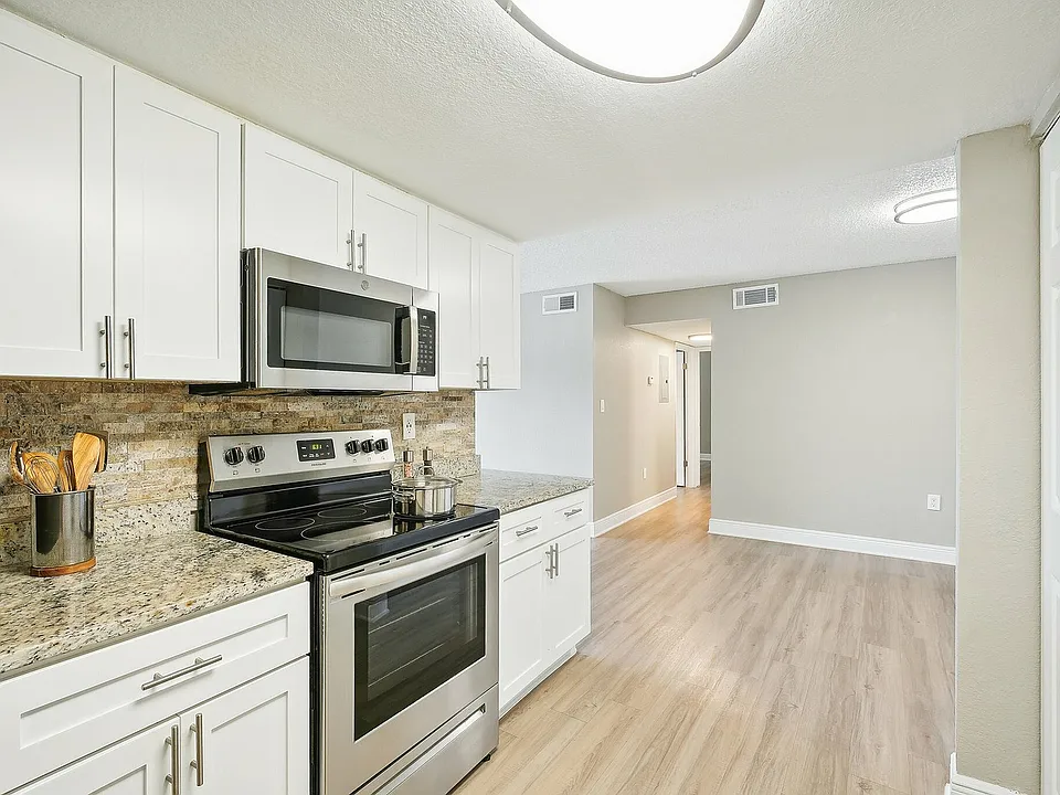 Modern kitchen with granite countertops, stainless steel appliances, and elegant cabinetry in a spacious apartment.
