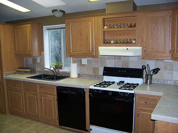 Kitchen has brand new tile counters and backsplash and black granite sink