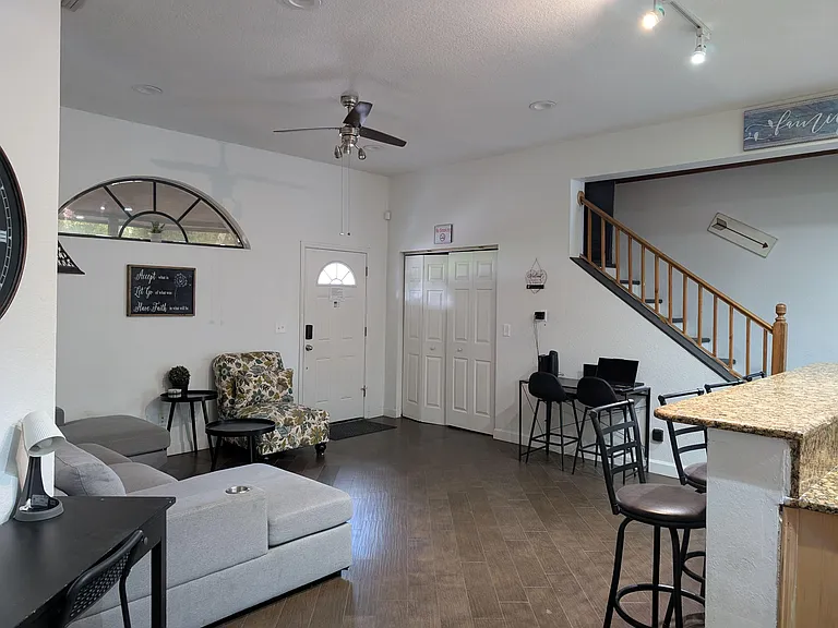 Open living area with sectional seating, a bar-height counter, and an arched window near the entry for added light.