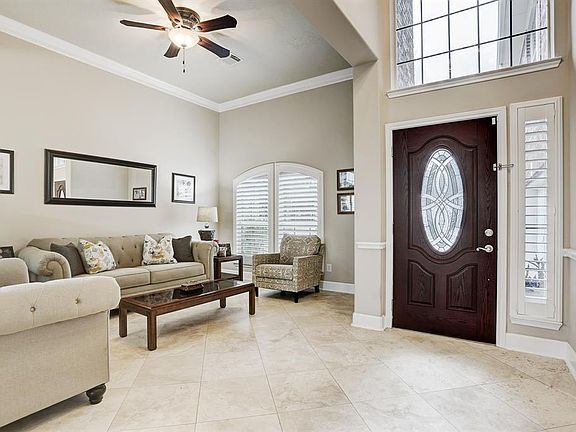 VIEW OF THE FORMAL LIVING AREA WITH CROWN MOLDING AND TILE FLOORS LAID ON A DIAGONAL.