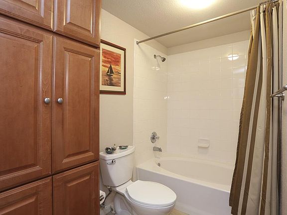 The bathroom also features a tub/shower combo with tile surround, and built- in stained maple cabinetry.