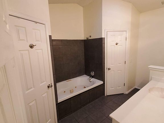 Master bathroom with vaulted ceiling, Jacuzzi tub, his and hers closet, and storage closet.