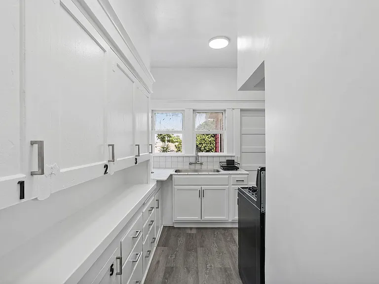 Efficient galley kitchen with ample white cabinetry, generous counter space, and a window over the sink for natural light.
