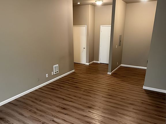 Inviting open-concept living area with elegant wood flooring and neutral walls, offering a spacious and versatile design. Inviting open-concept living area with elegant wood flooring and neutral walls, offering a spacious and versatile design.