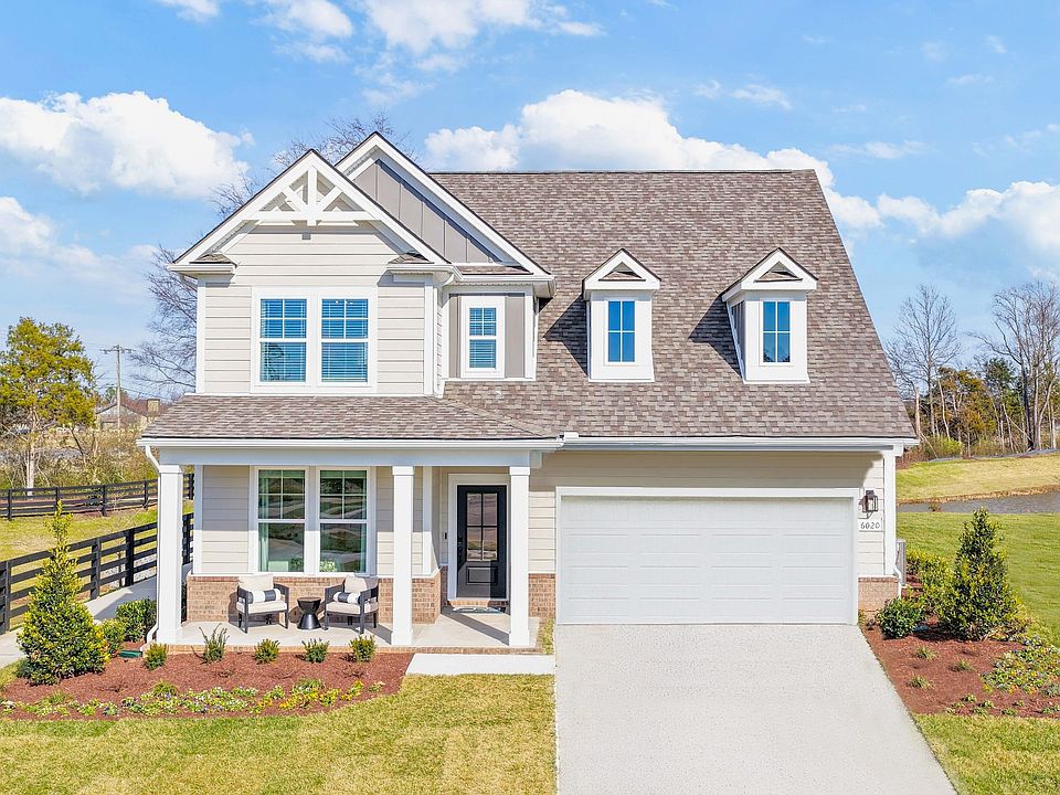 Exterior of home with neutral colored siding and brick accents with covered front porch and landscap