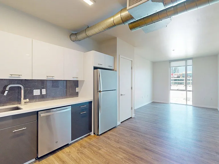 Apartment Kitchen with Stainless Steel Appliances, Dining and Living Room with Wood-Style Flooring.