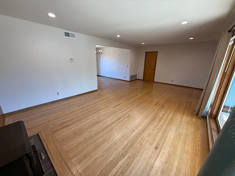 Bright, airy living room features bay window, hardwood flooring throughout.