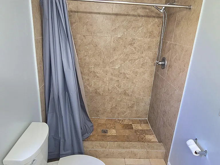 Full bathroom with a tiled walk-in shower, curtain rod, and easy-care tile flooring for simple daily upkeep.