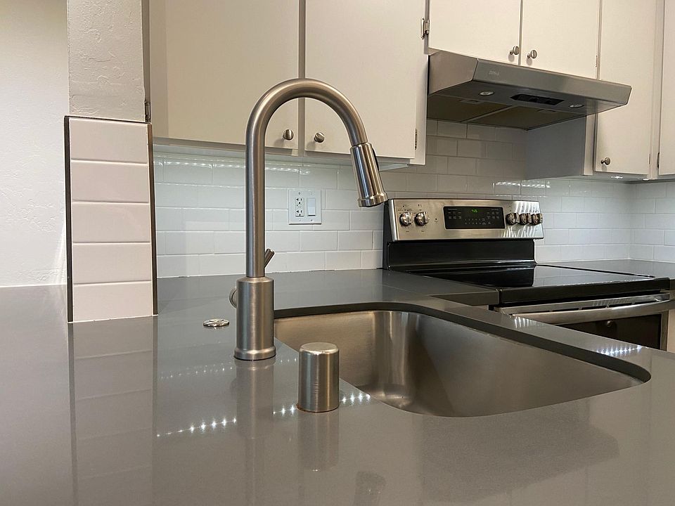 Large quartz peninsula, tile backsplash and deep stainless steel sink in kitchen