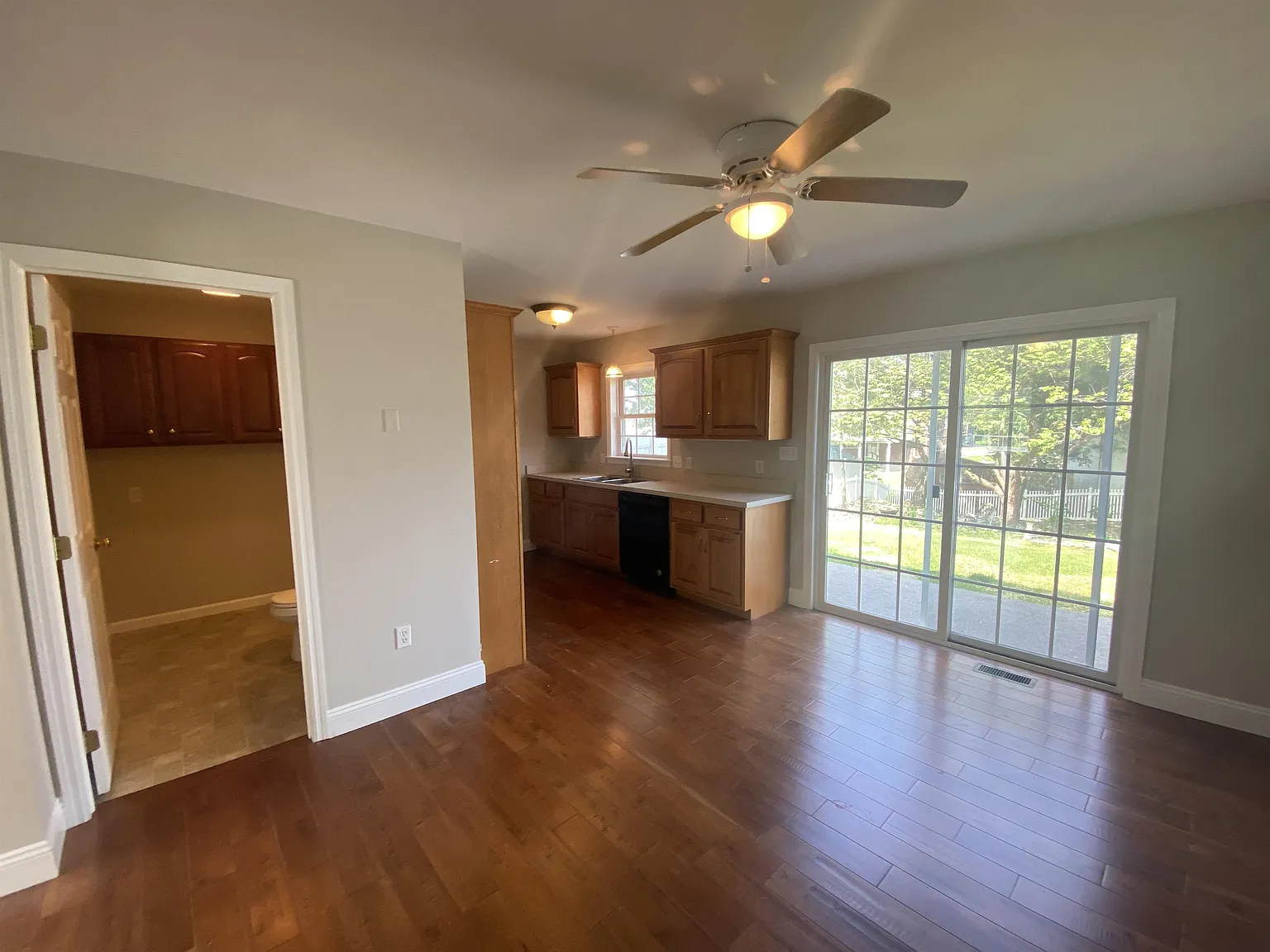 Large dining room kitchen combination with real hardwood flooring opening to private patio
