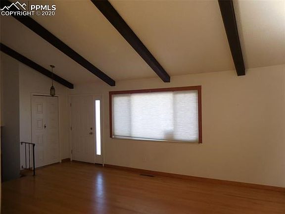 Large living room has an oak wood floor and vaulted beamed ceiling