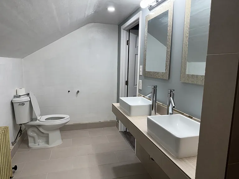 Upstairs bathroom is roomy and has two sinks and a walk in shower with bench.