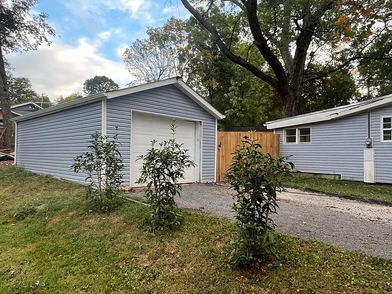 Garage with new privacy shrubs on property line next to empty lot.
