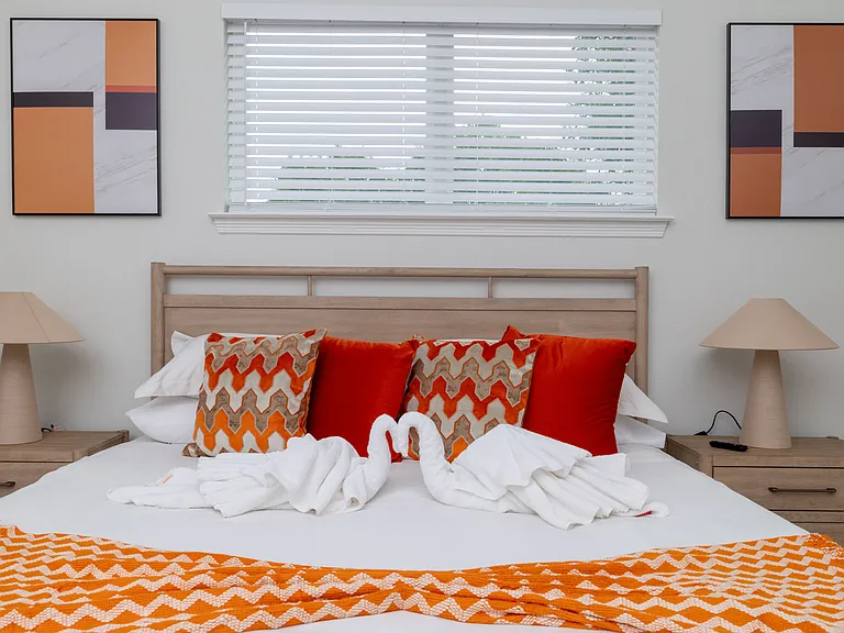 Primary bedroom features a king-size bed, corner chair, wall-mounted TV, backyard access, and an attached bathroom_your private retreat for comfort and relaxation.