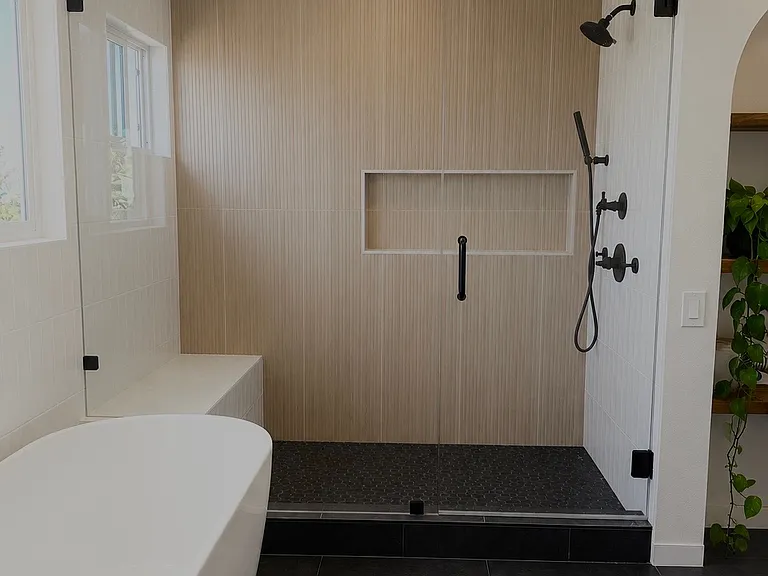 Luxuriously remodeled primary bathroom featuring a spa-inspired walk-in shower, freestanding soaking tub, designer tile finishes, and contemporary fixtures. Thoughtfully designed to create a private retreat for relaxation and comfort.
