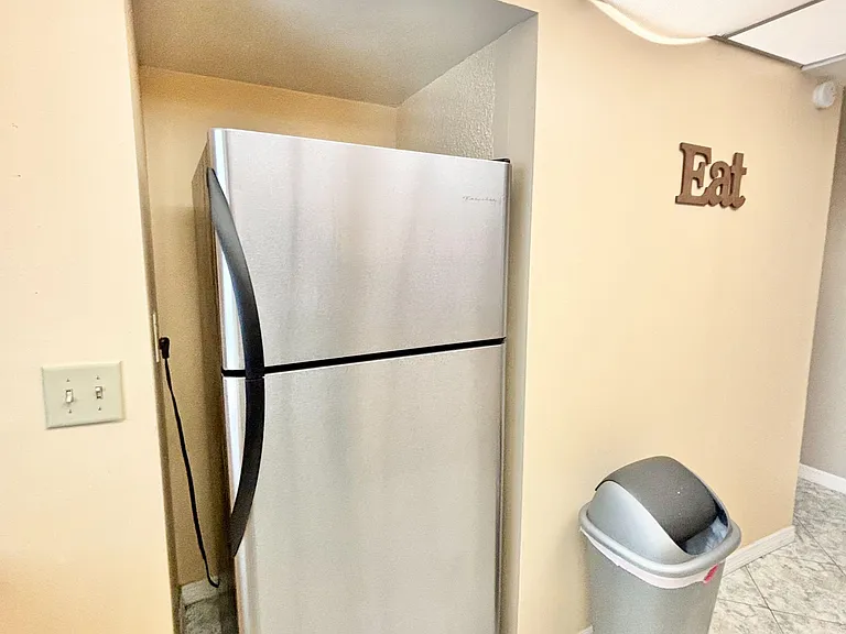 Kitchen area includes a full-size stainless refrigerator tucked into a dedicated alcove for efficient storage.