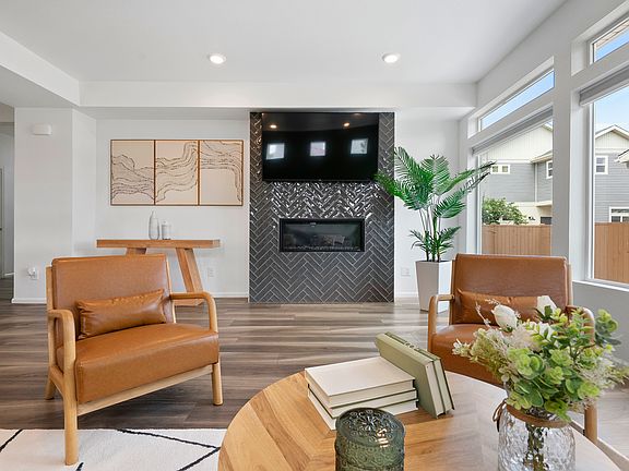 Bright living room with modern fireplace, stylish decor, and large windows for natural light. Comfortable seating perfect for relaxing or remote work. Enjoy a peaceful stay near parks and dining. Book your cozy, elegant retreat today!