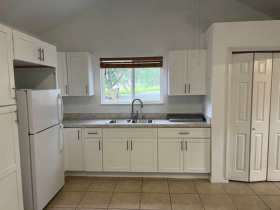 Another view that partially shows the pantry, full-sized refrigeration, and counter-top double burner appliance.