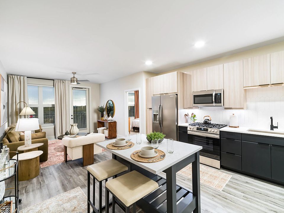 An open-concept apartment home with a central island, streamlined kitchen, and connected living areas designed for everyday flow and flexibility.
