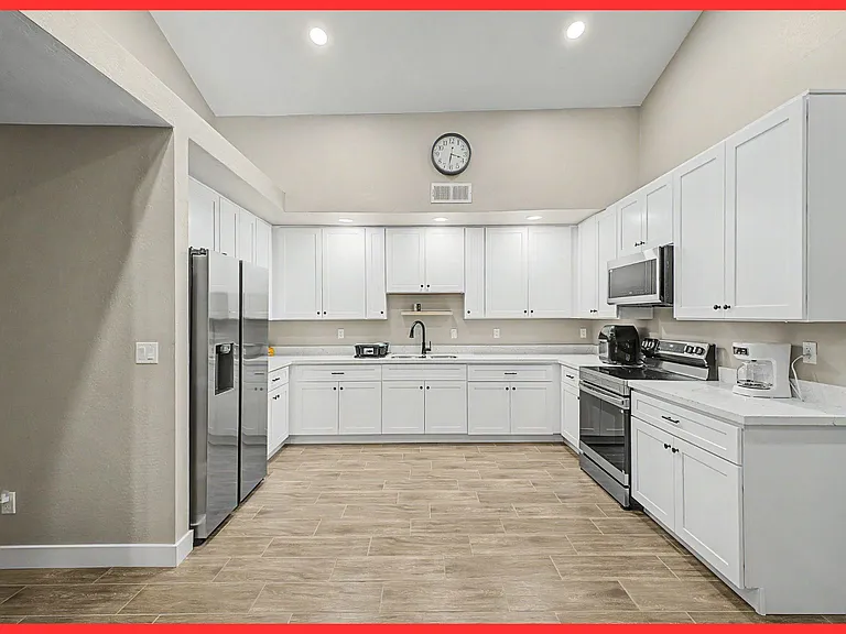 Spacious U-shaped kitchen with ample white cabinetry, generous counter space, and stainless steel appliances for easy meal pr