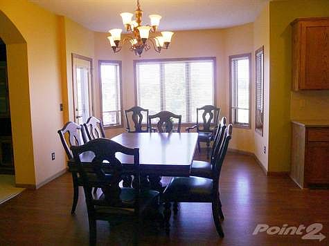 Oversized dining area with bay window and door leading to deck with stairway to access aggregate patio in backyard