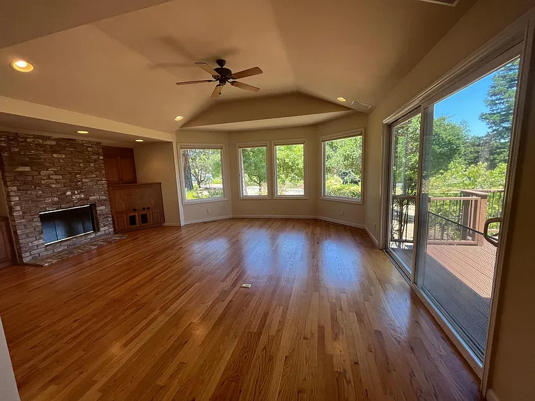 Grand family room features built-in cabinetry, vaulted ceiling, hardwood flooring, bay windows and a patio door that leads to a huge inviting outdoor deck beckoning for entertainment or relaxation.