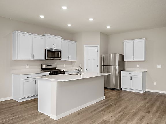 The kitchen has stainless steel appliances and plank flooring.