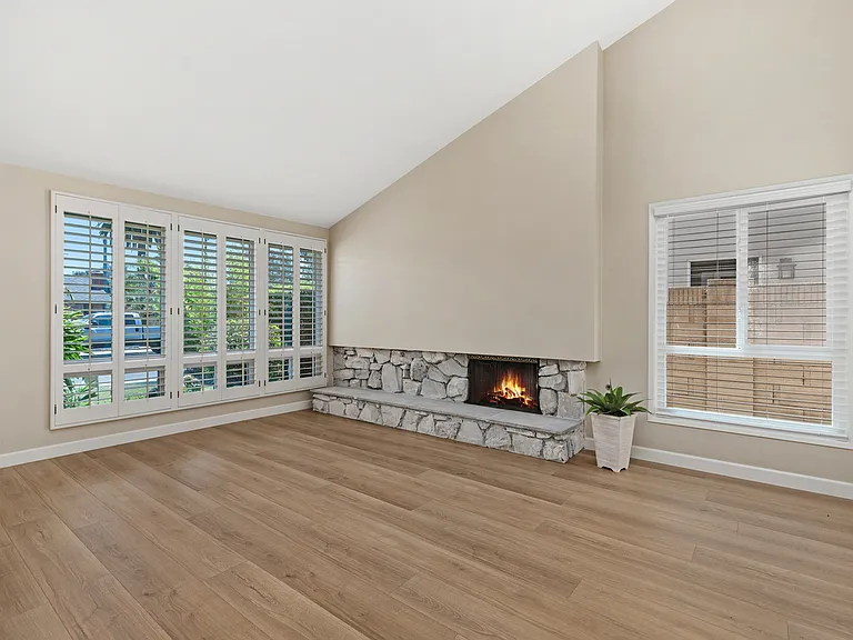 Living Room with high ceilings, natural stone fireplace & hearth, smooth ceilings, dual pane windows and beautiful "wood-like" flooring