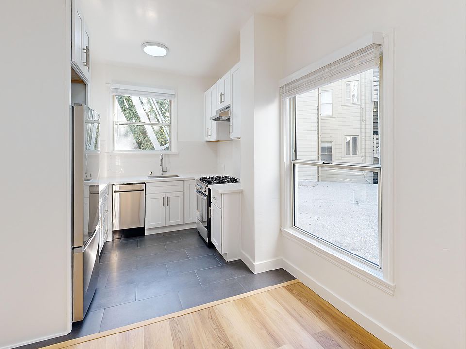 Kitchen with multiple cabinets, refrigerator, stove, range hood, and sink