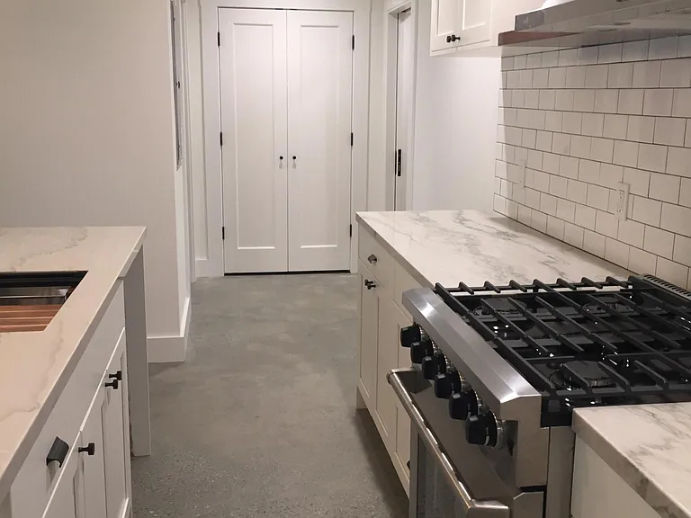 Kitchen looking down hallway to a closet. Bathroom entry is on the left and laundry entry is on the right at the end of the hallway.