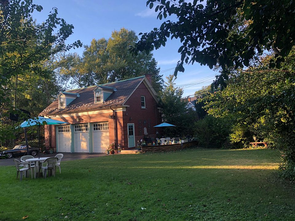 Carriage House, private raised granite patio with wall fountain, planters, table, chair and umbrella. Ledge stone seating wall. Fenced park like yard.