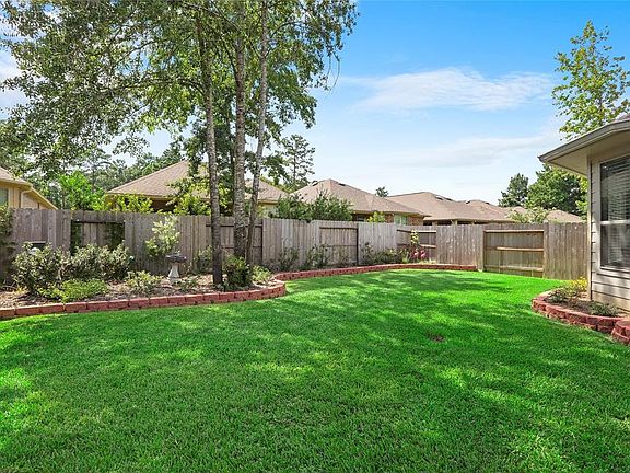 Shade trees and lush landscaping line the backyard.