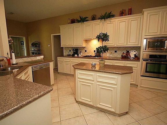 Kitchen has solid wood cabinets, tile floor, stainless steel appliances, and Avanza countertops.