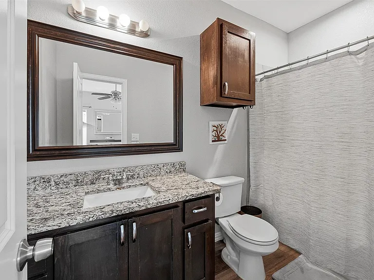 Bathroom vanity featuring a speckled countertop, undermount sink, and dark wood-finish cabinetry with silver hardware