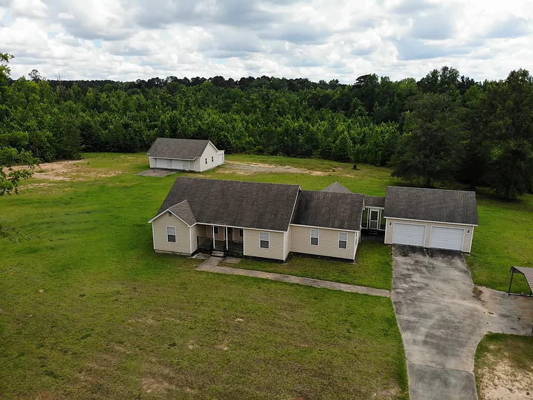 House has 2 car attached garage and 1 car carport off to the right; also pictured: 2 car detached garage with additional boat garage behind it
