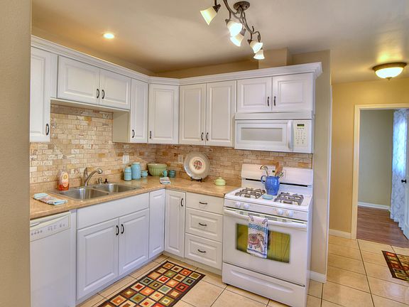 Kitchen View #1with Stone Backsplash, gas range, over the range microwave, dish washer, corner cabinet with lazy susan wire racks.