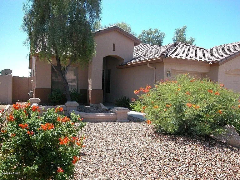 The front yard is landscaped nicely with colorful plants and desert landscaping.