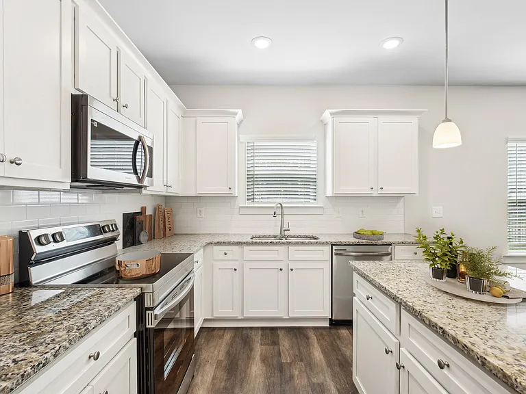 Spacious kitchen with an island, ample storage, stainless steel appliances and view into the living room.