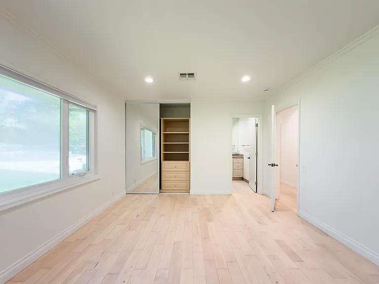 Bright bedroom with mirrored closet doors and built-in shelving overlooks the yard in this Beverly Hills luxury rental at 1094 Garden Lane, a 90210 lease option.