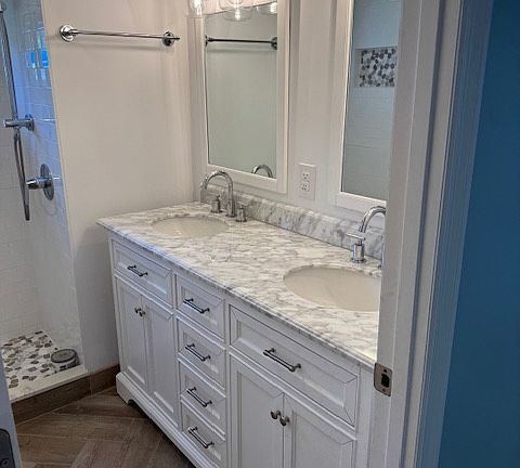 Bathroom has double vanity sink with granite countertop, chrome facets and designer lighting.