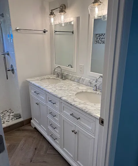 Bathroom has double vanity sink with granite countertop, chrome facets and designer lighting.