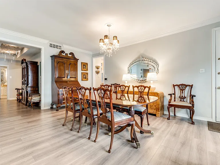 Dining area featuring light wood-finish flooring, a tiered chandelier, and crown molding