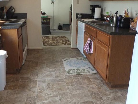 VIEW FROM LIVING ROOM , FACING KITCHEN AND DEN, REFRIGERATOR AND HALLWAY TO RIGHT , GOING BACK TO BATHROOM AND BEDROOMS