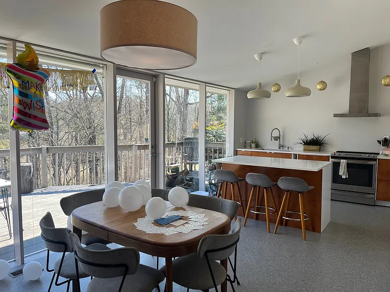 kitchen-dining combo with door to deck and amazing view of woods, sunrise.